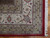 Corner detail showing cream floral border, red outer guard stripe and clean white cotton fringe