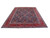 Angled floor view of large navy and red Tabriz wool rug showing ivory guard borders