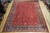 9'11" x 12'8" Tabriz rug laid flat on light wood showroom floor, red field