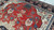 Pile close-up in raking light, rust red wool with cream palmettes and blue rosette blossoms