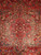 Central stepped medallion detail with cross panels, serrated ivory leaves and blue rosettes on red