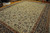 Angled showroom view of oversize 13x19 Persian rug, cream ground framed by rust and navy borders
