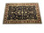 Angled full view of oversize black and burgundy hand-knotted wool rug on white background