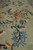 Macro of hand-knotted wool pile showing blue star blossoms and an orange rosette on green