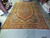 Oversize 11x18 Sarouk rug laid flat on warehouse floor showing coral field and gold border