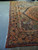 Angled corner shot of 1930s Persian rug with scalloped navy border and rose vine guard