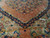 Medallion edge detail where coral field meets indigo outline and camel spandrel floral work