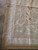 Rug corner close-up highlighting flat tapestry weave, peach guard stripes and a small cream rosette