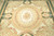 Close view of ivory oval medallion, rose garlands and sage green field on this Aubusson rug