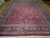 Angled floor view of oversize red Persian rug with ivory guard borders and navy main border
