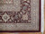 Corner detail showing burgundy border, boteh guard stripe, ivory fringe and dense wool pile