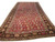 6x14 antique Persian Kerman gallery rug angled view showing red paisley field and dark floral border