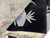 Corner detail showing lavender grey vase and bamboo leaves woven on deep black ground