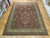 Red and ivory hand-knotted wool rug displayed on parquet floor inside the Freeport rug warehouse