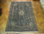 9'4" x 12'9" Persian Kashan rug laid on parquet floor showing full navy border layout
