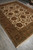 Cream and sage Indian floral rug photographed on grey tile floor from a corner angle
