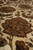 Macro of hand-knotted wool pile showing rust and olive petal shading on cream ground