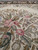Pink roses, lavender blossoms and olive foliage stitched across the soft ivory field close up