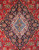 Close-up of ivory and light blue medallion core surrounded by navy palmettes on crimson ground