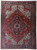 Full overhead view of red Persian Heriz rug with navy diamond medallion and ivory corner spandrels