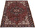 Angled floor view of brick red and navy Heriz rug showing ivory corner spandrels