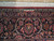 Close-up of woven signature cartouche in the navy border above ivory fringe of Persian rug