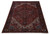 Angled floor shot showing the hand-knotted wool pile and navy palmette border of this Heriz rug