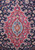 Close-up of red medallion with light blue rosette center surrounded by navy palmettes and vines
