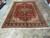 8'2 x 11'6 Persian Heriz rug displayed on showroom tile floor, red field, navy border