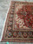 Hand-knotted Heriz corner with ivory fringe, teal border cartouches and deep red floral field