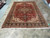 Whole semi-antique Heriz rug laid flat, red field, navy border and ivory fringe both ends