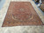 Antique Persian rug from the 1940s displayed flat, red field framed by deep navy floral borders