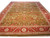 Angled view of 9'8" x 14'6" olive green Agra design rug with coral red floral border