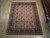 8x10 hand-knotted wool Oriental rug with camel field displayed on light wood showroom floor