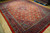 Angled view showing the orange red field and deep indigo border of this 10x13 rug
