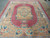 Large 10 x 13 Aubusson design rug viewed lengthwise, rose border framing gold and pink interior