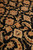 Detail of blossoms, leaf cartouches and vine scrolls in beige and gold across the black field
