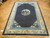Antique hand-knotted wool rug seen lengthwise, sky blue guard band framing the dark indigo ground
