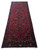Angled floor view showing the long red runner, dark navy border and ivory cotton fringe ends