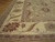 Corner detail showing ivory main border, burgundy rosettes and serrated leaves on hand-knotted wool pile