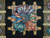 Close-up of central rosette medallion with teal and coral ribbons over gold lattice on black wool