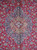 Close-up of ivory and blue central medallion surrounded by red field and curling floral vines