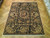 7'10" x 9'9" Chinese wool rug displayed on parquet floor showing full black field and borders