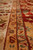 Narrow guard borders in gold, cream and sage framing the red field of the rug