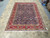 Living room size blue and red Persian Tabriz area rug laid flat for scale