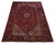 Angled view of red and navy hand-knotted Heriz rug showing ivory spandrels and wide border