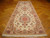 Ivory wool and silk Tabriz runner displayed lengthwise on parquet wood floor with white fringe
