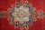 Close-up of navy medallion with ivory palmettes, turquoise rosette and coral flowers on red wool