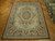 8 x 10 Chinese Aubusson rug displayed flat on parquet floor beside a stack of rugs