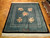 Green Art Deco rug displayed on parquet floor showing ivory fringe and five pink floral bouquets